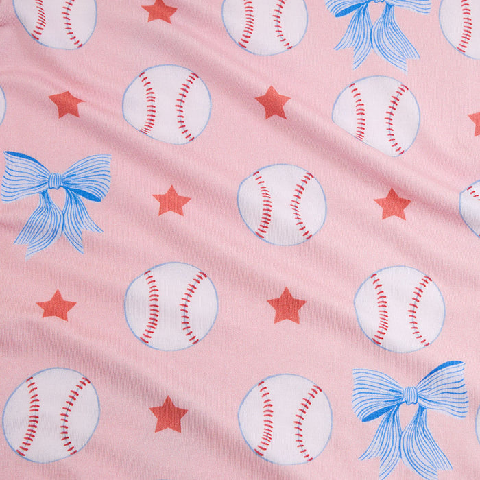 Fabric pattern of baseballs, stars, and blue bows on a pink background