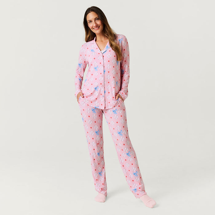 Woman wearing pink pajamas with baseball pattern on a light gray background