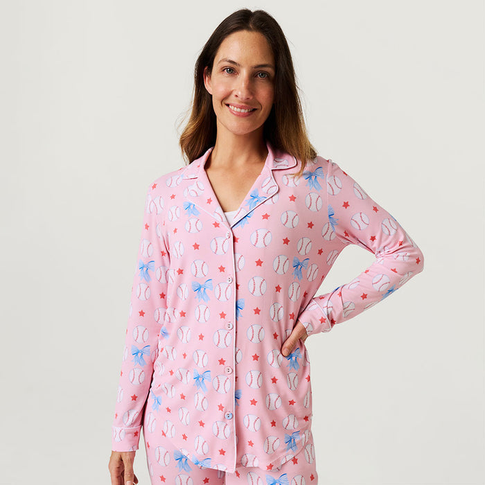 Woman wearing a pink pajama set with baseball pattern on a plain background