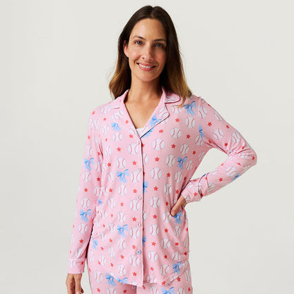 Woman wearing a pink pajama set with baseball pattern on a plain background