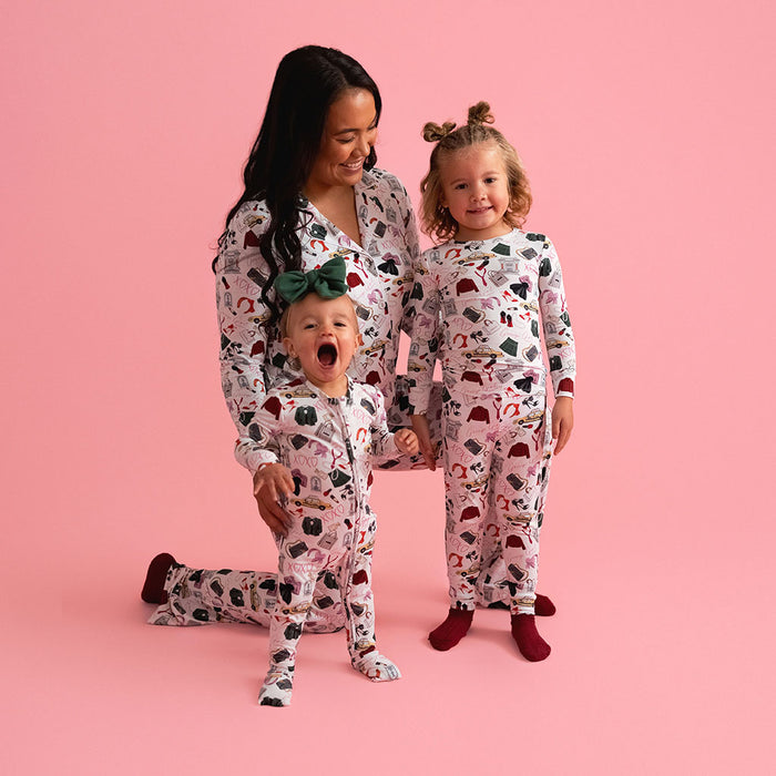Family of three wearing matching pajamas on a pink background