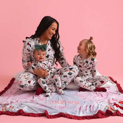Woman and two children in matching pajamas on a pink background