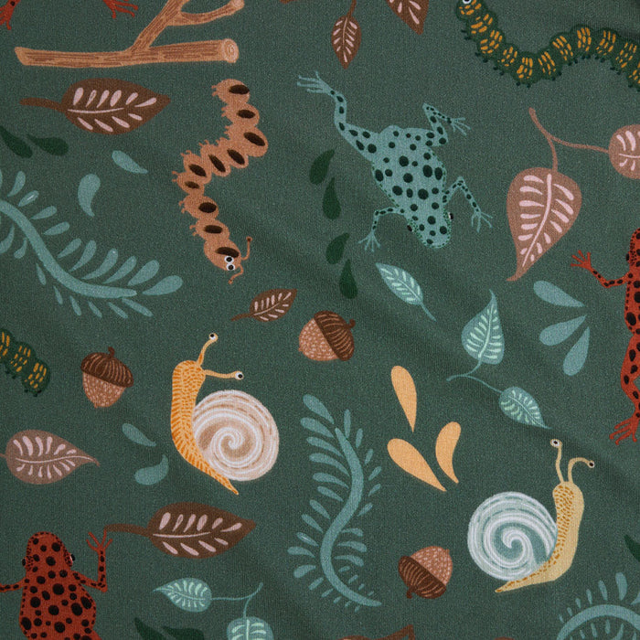 forest creatures themed fabric close up with frogs, snails, acorns, leaves, sticks and caterpillar