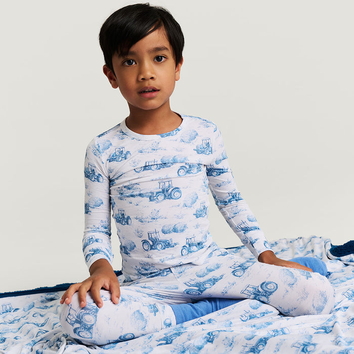 Child wearing a blue and white pajama set with vehicle pattern on a light gray background
