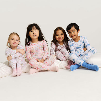 Four children wearing pajamas sitting on a bed against a white background