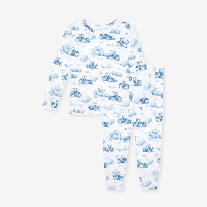 Baby pajama set with blue tractor pattern on a white background