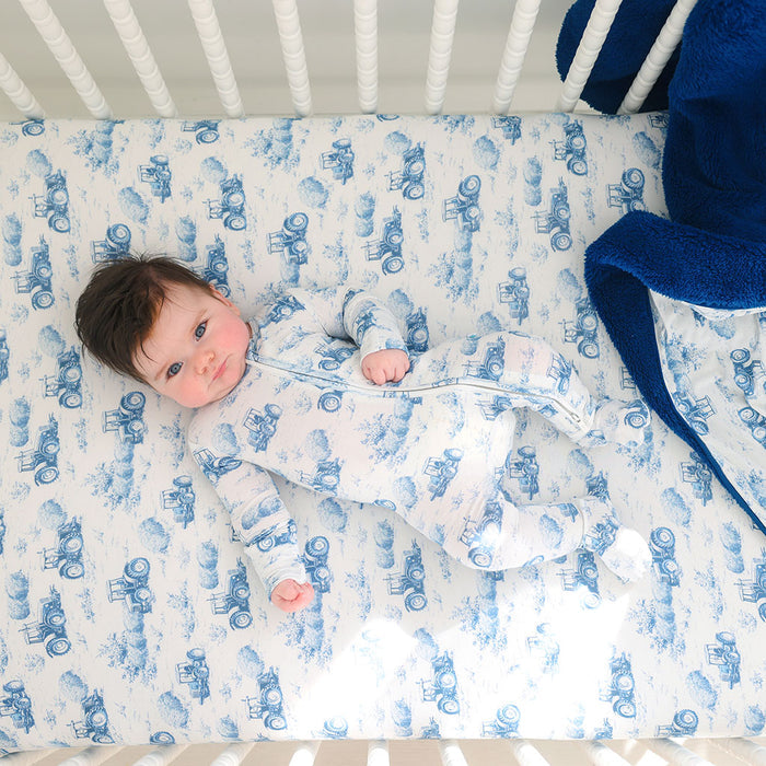 Baby lying in a crib with blue and white patterned bedding