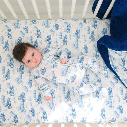 Baby lying in a crib with blue and white patterned bedding