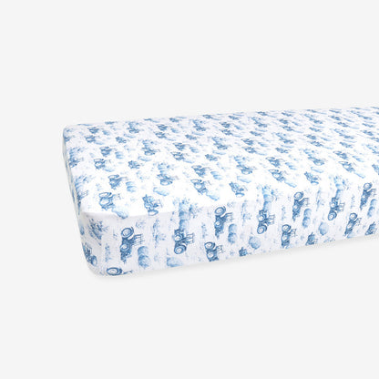 Fitted crib sheet with blue tractor pattern on a white background