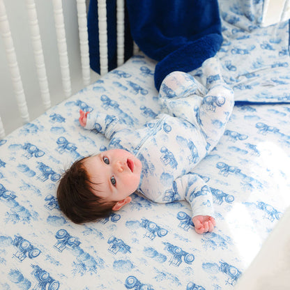 Baby lying on a crib with blue and white patterned bedding