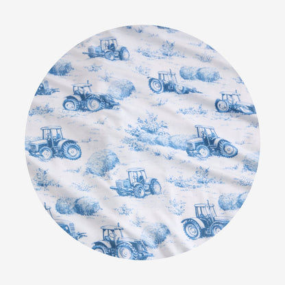 Round fabric swatch with blue tractor and hay pattern on a white background