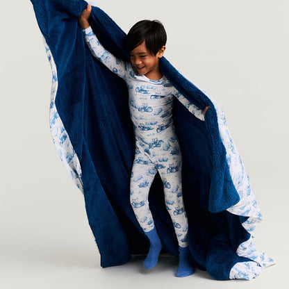Child wearing a blue and white patterned onesie with a matching blanket.