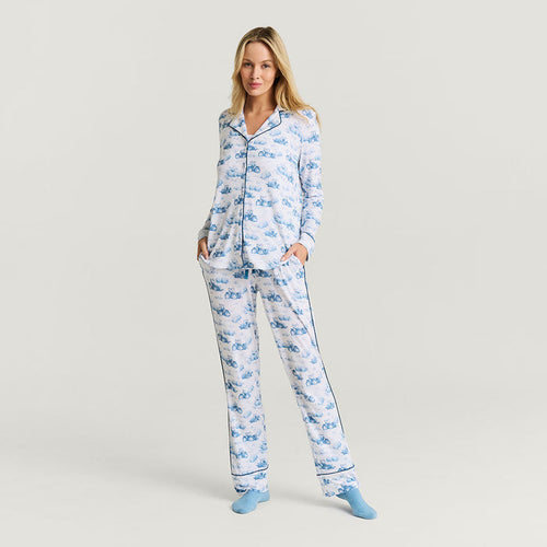 Woman wearing a blue tractor print pajama set on a light gray background