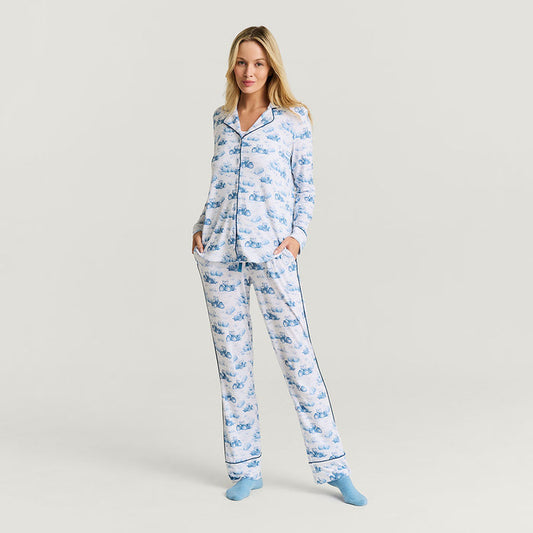 Woman wearing a blue tractor print pajama set on a light gray background