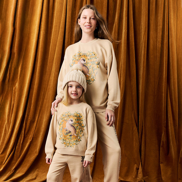 Adult and child wearing matching tan Harry Potter Hufflepuff printed sweatshirt and jogger sets.