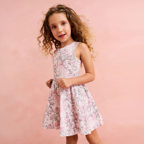 close up of child wearing a floral and bow printed dress