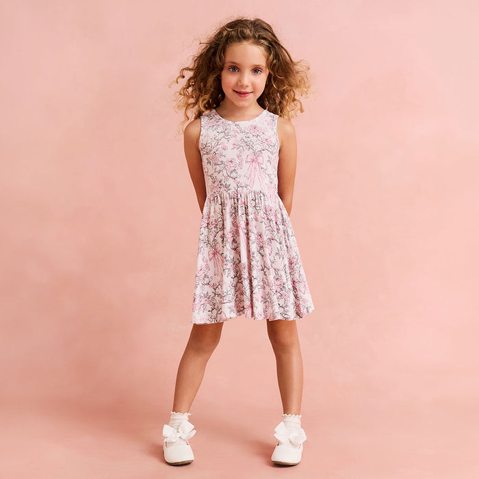 child wearing a floral and bow printed dress on a pink background