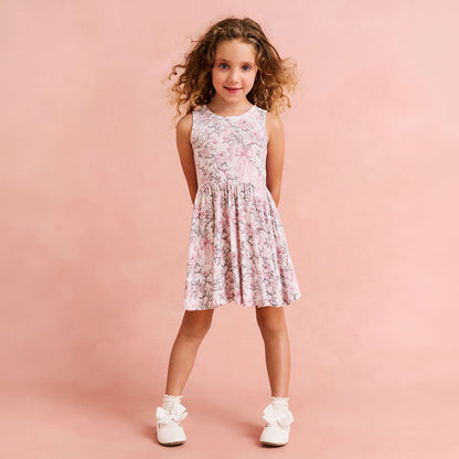 child wearing a floral and bow printed dress on a pink background