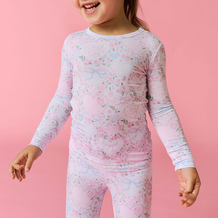 Detail image of a child wearing a floral long-sleeve pajama set on a pink background