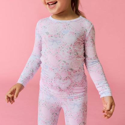 Detail image of a child wearing a floral long-sleeve pajama set on a pink background