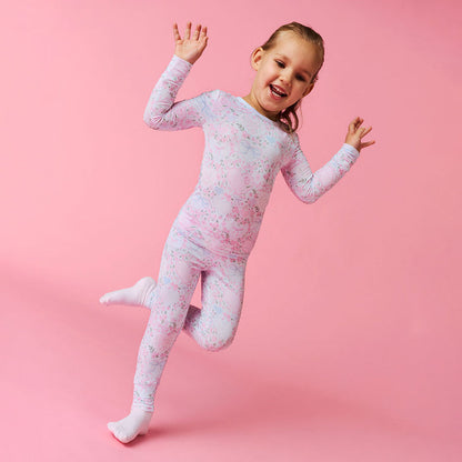 Child wearing a pink and white patterned pajama set on a pink background