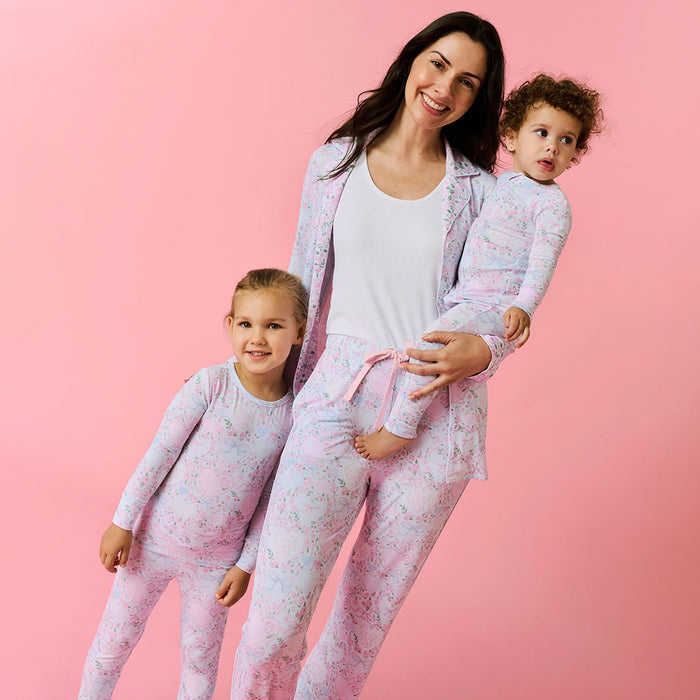Woman and two children wearing matching pink pajamas against a pink background