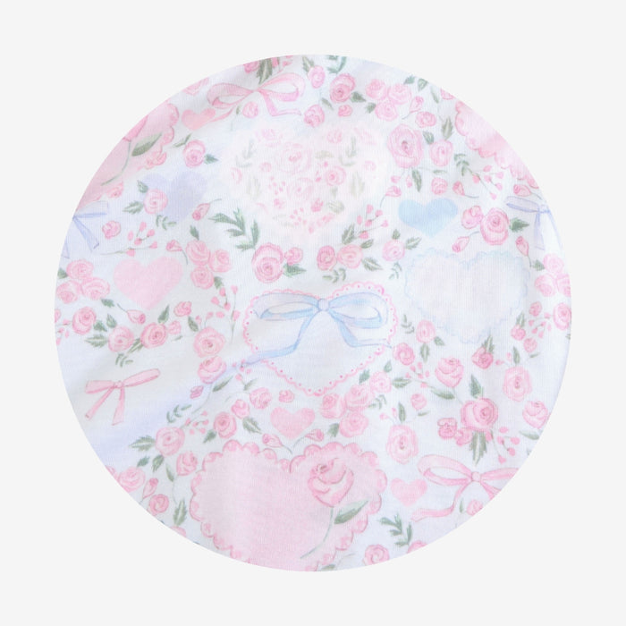 Round fabric swatch with pink floral and bow pattern on a white background