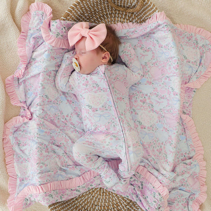 Baby lying on a floral blanket with a pink bow, wearing a matching outfit.