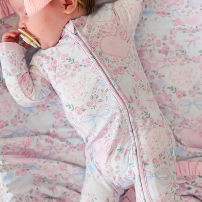 Baby in a floral one piece on a matching blanket