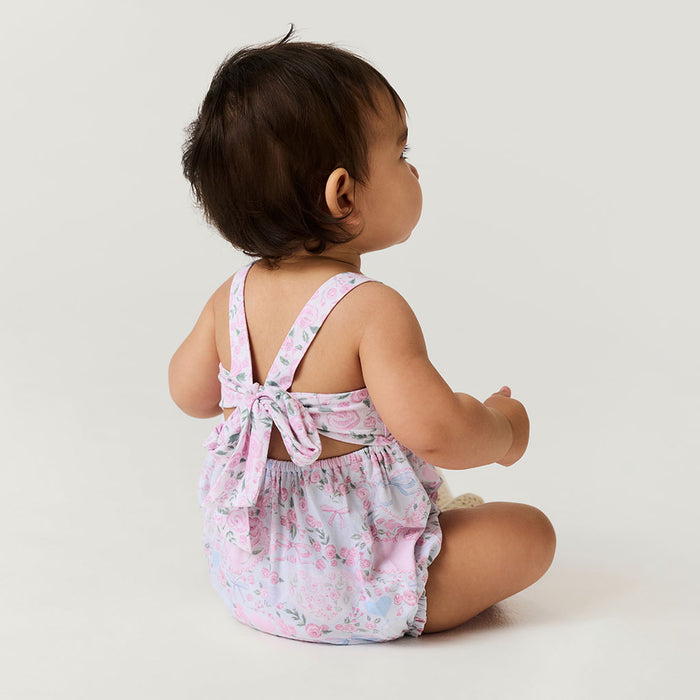 Baby wearing a floral romper sitting on a white background
