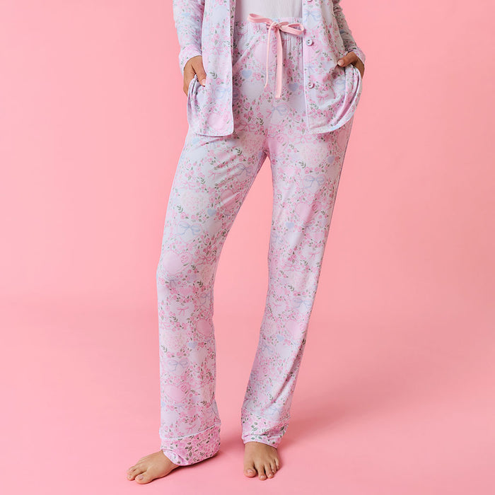 Person wearing a pink floral pajama set on a pink background