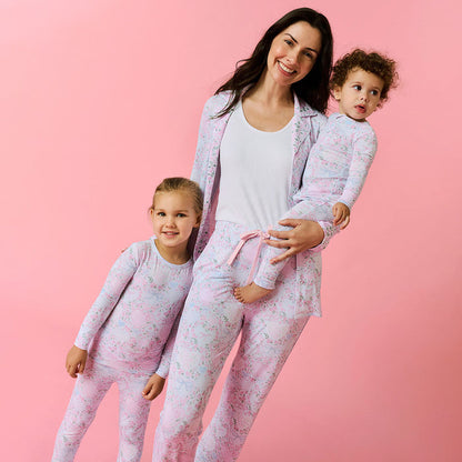Woman and two children wearing matching pink pajamas against a pink background