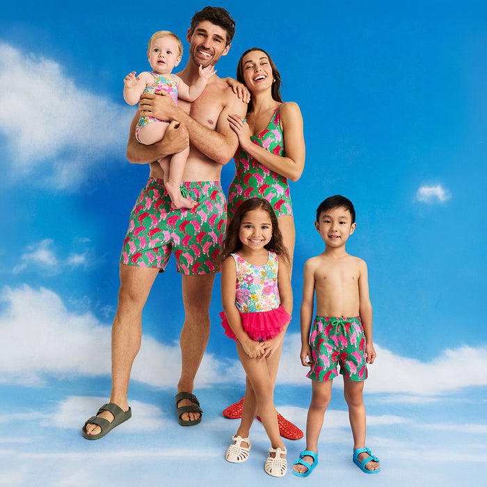 Family of five wearing matching swimwear against a blue sky background