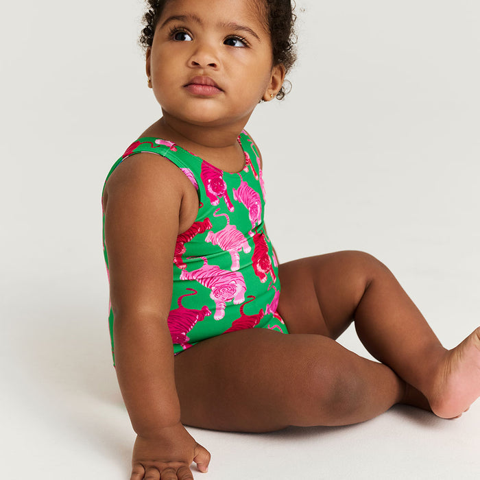 Child wearing a green and pink tiger-patterned swimsuit on a white background
