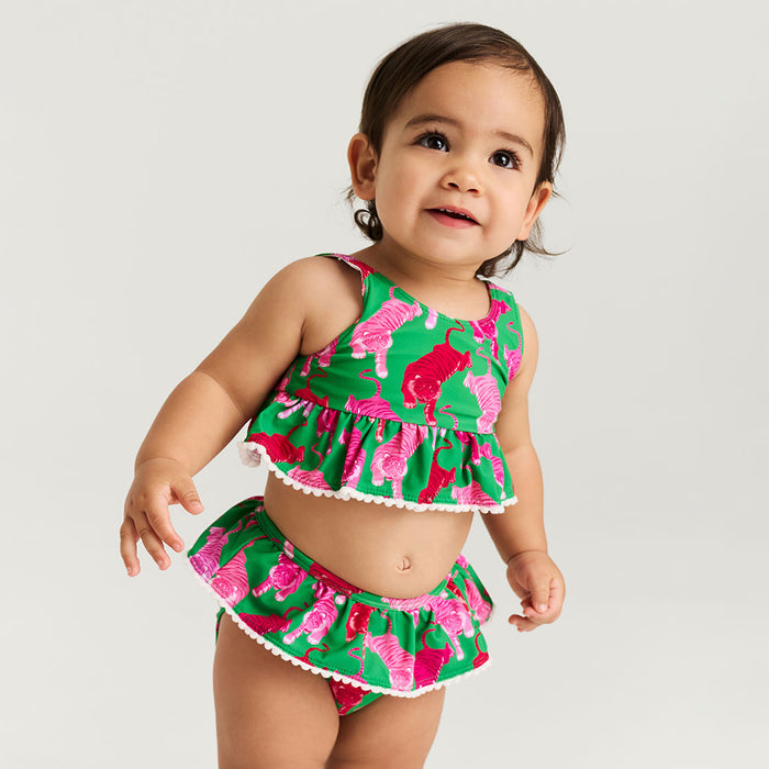 Child wearing a green and pink floral two-piece swimsuit on a white background
