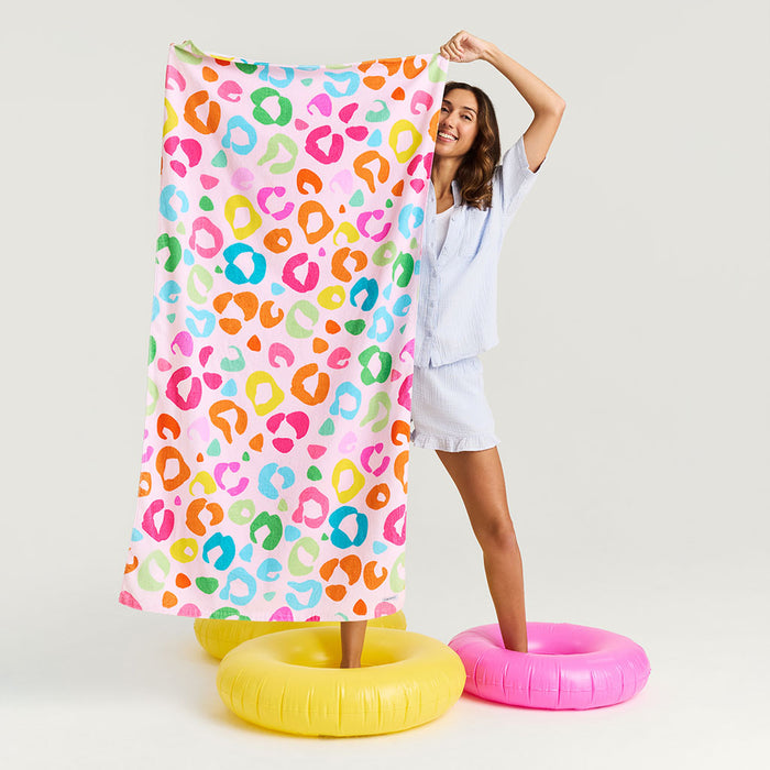 Person holding a colorful leopard print towel with pool floats in the foreground