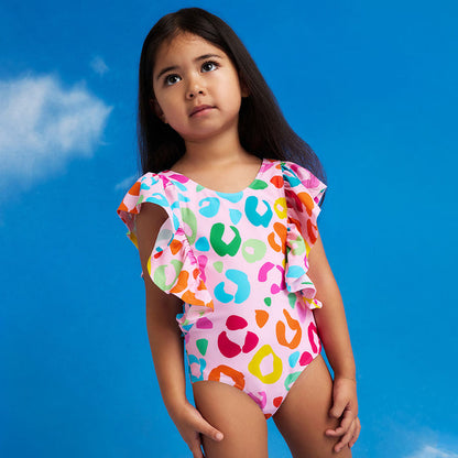 Young girl wearing a colorful leopard print swimsuit against a blue sky background