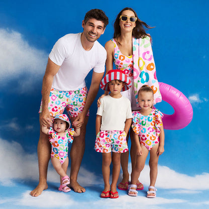 Family of five wearing matching colorful swimwear against a blue sky background