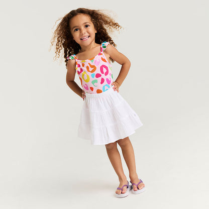 Young girl wearing a colorful top and white cotton crinkle skirt with a white background
