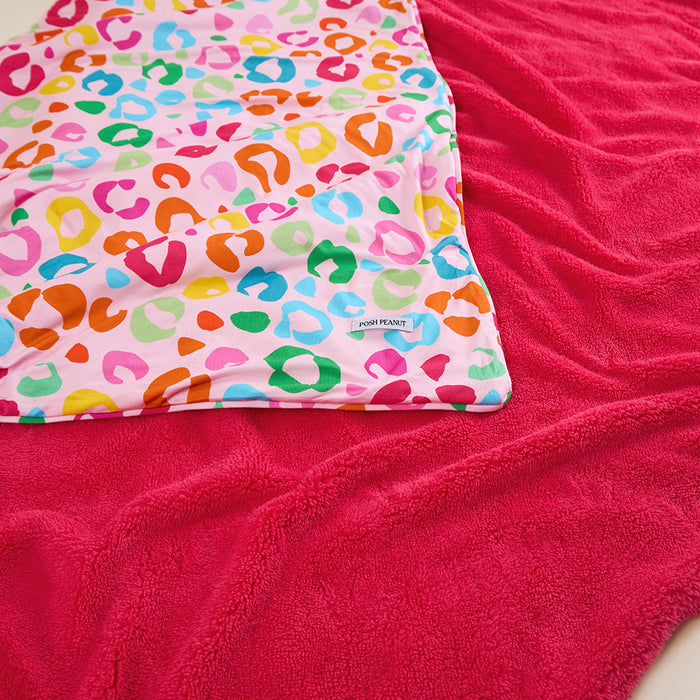 Colorful leopard print blanket on a pink surface