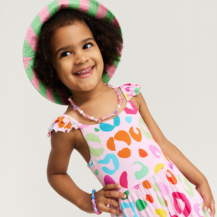 Child wearing a colorful jumpsuit with a pattern of multicolored shapes on a plain background