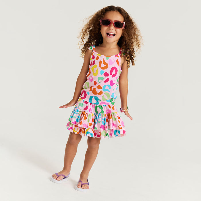 Child wearing a colorful skirt with a pattern of multicolored shapes on a white background