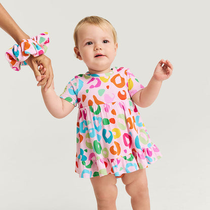 Child wearing a colorful dress holding a hand against a plain background
