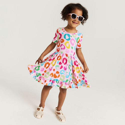 Child wearing a colorful dress with a pattern and sunglasses on a white background