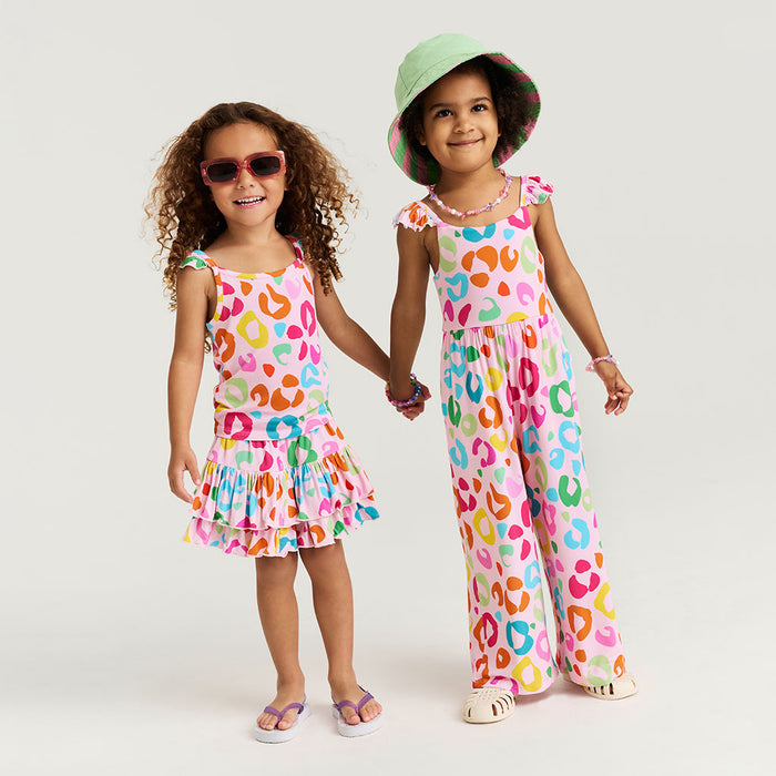 Two children wearing colorful animal print outfits on a plain background