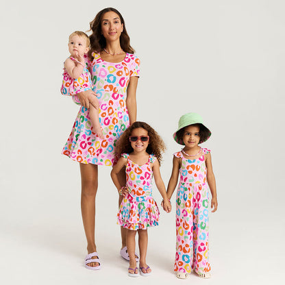 Woman holding a baby and two children wearing matching colorful outfits on a white background