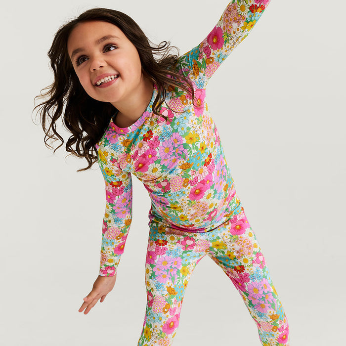 Child wearing a colorful floral pajama set made of bamboo viscose on a white background