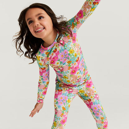 Child wearing a colorful floral pajama set made of bamboo viscose on a white background