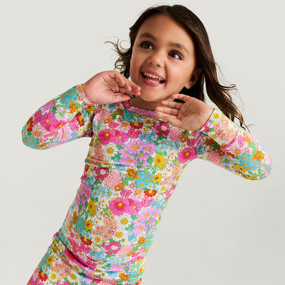 Child wearing a colorful floral long-sleeve shirt on a light gray background