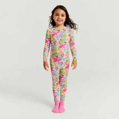 Child wearing a colorful floral pajama set made of bamboo viscose on a white background